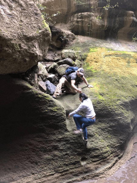 People climbing large rocks on an outdoor adventure.
